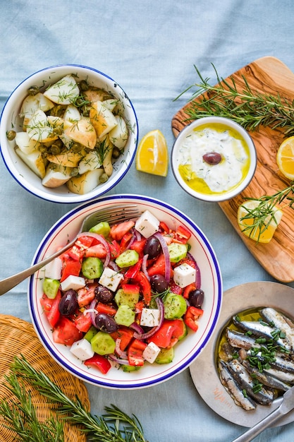 Vista dall'alto della scena della tavola di cibo greco Varietà di articoli tra cui la salsa di cetriolo insalata greca Tzatziki Filetti di acciughe Patate al limone