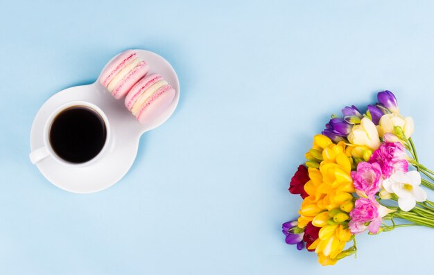 Vista dall'alto della tazza di caffè e bouquet di fiori colorati su sfondo azzurro