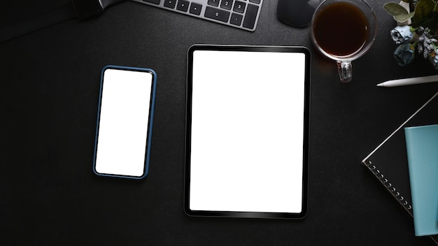 Vista dall'alto della tazza di caffè e del taccuino dello smartphone della compressa digitale su pelle nera