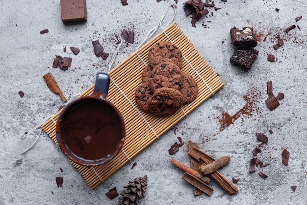 Vista dall'alto della tazza di cioccolata calda e pezzi di biscotti su sfondo di cemento chiaro