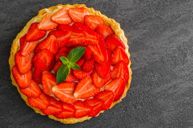 Vista dall'alto della torta di fragole fresche con frutti di bosco su grigio