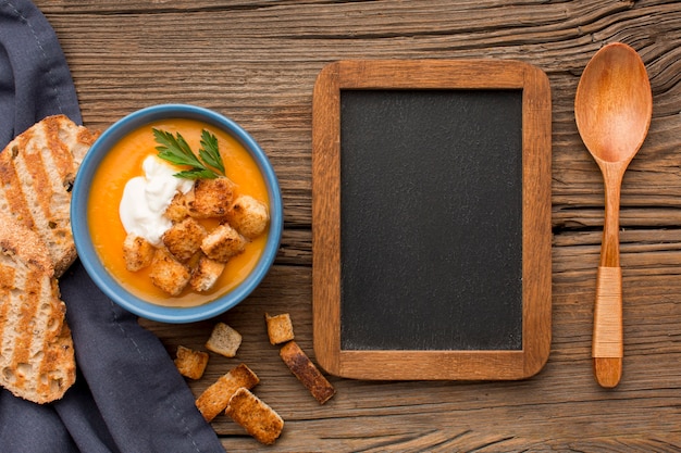 Vista dall'alto della zuppa di zucca invernale con lavagna e crostini di pane