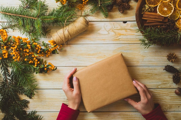 Vista dall'alto delle mani femminili che tengono una scatola con spazio per la copia La donna crea un regalo di Natale con materiali ecologici