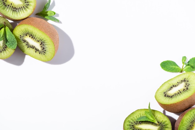 Vista dall'alto delle metà mature del kiwi vicino alla menta piperita verde su bianco