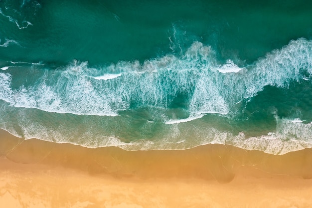 Vista dall'alto delle onde dell'oceano che si infrangono sulla spiaggia sabbiosa