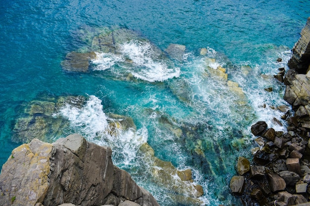 Vista dall'alto delle onde turchesi che si infrangono sulle rocce