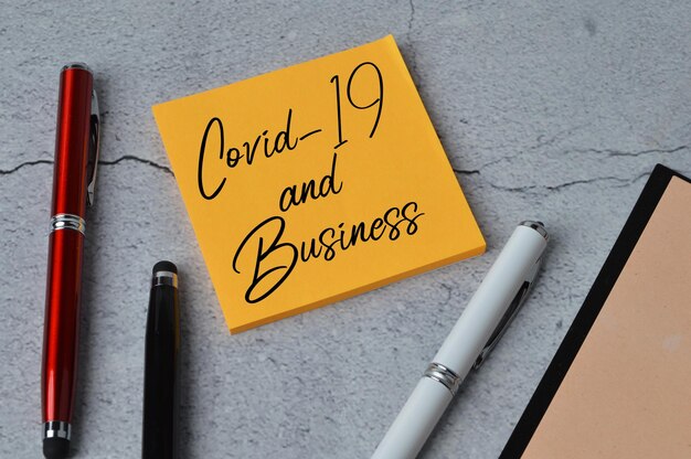 Vista dall'alto delle penne e delle note scritte con COVID19 AND BUSINESS