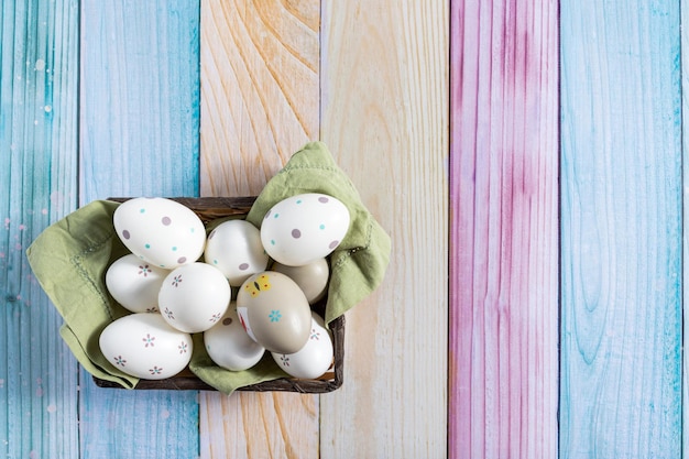 Vista dall'alto delle uova di Pasqua dipinte in un cestino su uno sfondo di legno colorato