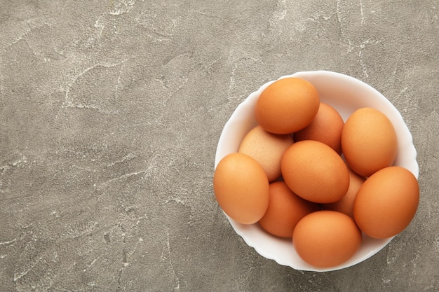Vista dall'alto delle uova marroni crude su piatto su sfondo grigio Le uova sono un ingrediente comune in cucina