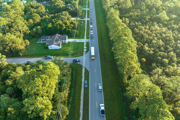 Vista dall'alto dello scuolabus giallo americano standard che raccoglie i bambini alla fermata della città rurale per le loro lezioni al mattino presto Trasporto pubblico negli Stati Uniti