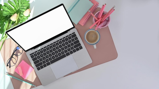 Vista dall'alto dello spazio di lavoro moderno con portamatite per laptop, tazza da caffè e pianta d'appartamento