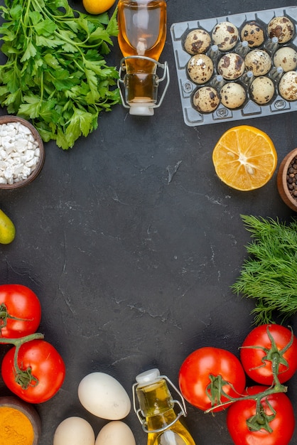 Vista dall'alto dello spazio vuoto tra le verdure fresche cadute bottiglia di olio uova di limone fasci verdi su sfondo nero