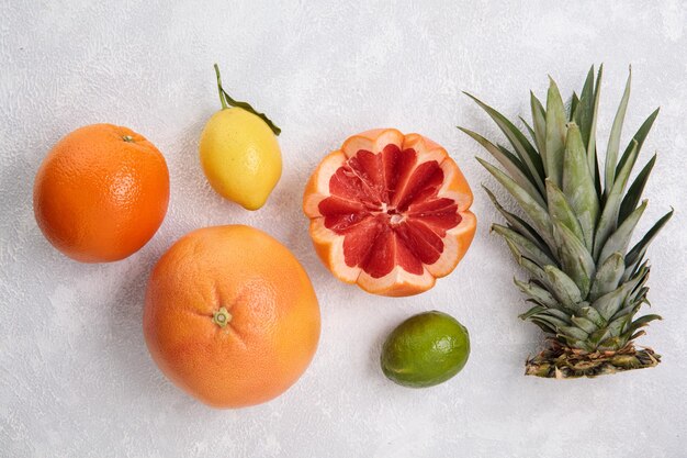 Vista dall'alto di agrumi come arancia limone mandarino lime pompelmo tagliato con foglie di ananas su sfondo bianco
