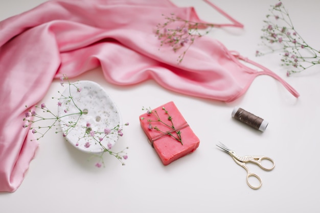 vista dall'alto di articoli di bellezza femminili regalo in tessuto di seta rosa e forbici decorative