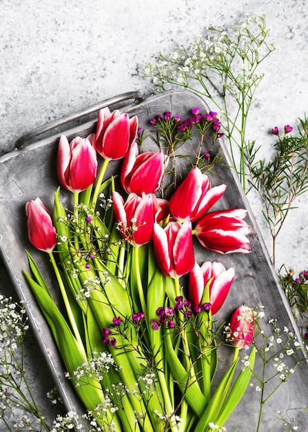 Vista dall'alto di bellissimi tulipani rosa e bianchi, gypsophila e fiori di cera su un vecchio vassoio di metallo