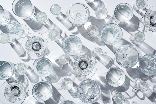 Vista dall'alto di bicchieri trasparenti con acqua limpida su sfondo bianco