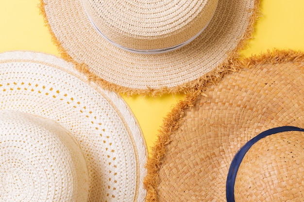 Vista dall'alto di cappelli da spiaggia di paglia su sfondo giallo