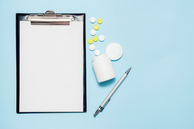 Vista dall&#39;alto di carta bianca per la scrittura di prescrizione del medico. Pillole sul blu