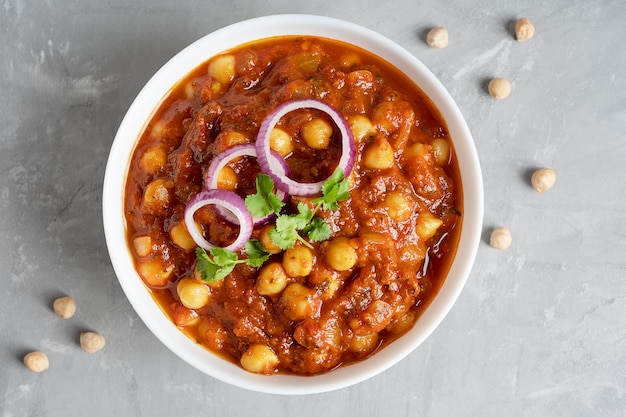 Vista dall'alto di chole masala cibo vegano indiano fatto di ceci e pomodori sul tavolo di cemento grigio