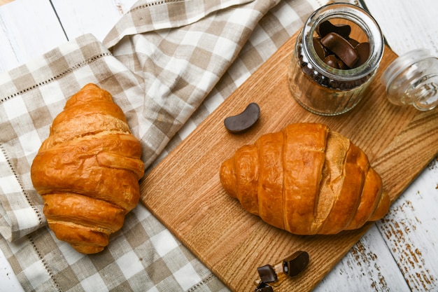 Vista dall'alto di cornetti al cioccolato francese. l'inizio della mattina. Cornetto francese fresco. Tazza di caffè e croissant al forno freschi su un fondo di legno. Vista dall'alto