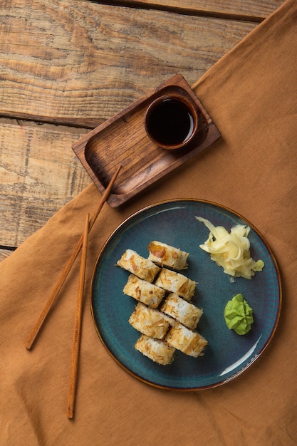 Vista dall'alto di deliziosi involtini di sushi con ingredienti su un tavolo di legno