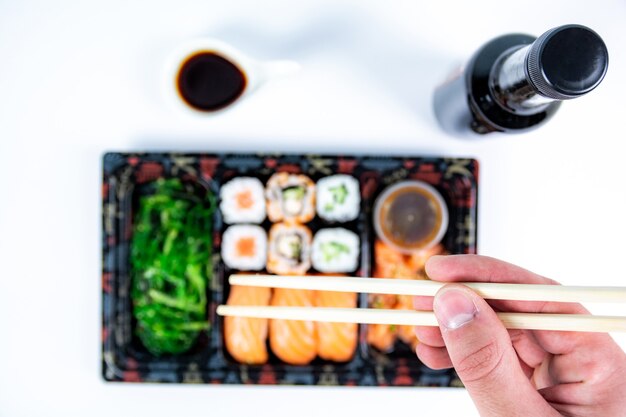 Vista dall'alto di deliziosi pezzi di sushi di varietà su vassoio di legno. Vista dall'alto del cibo giapponese con huramaki, maki, panini, nigiri, alghe e riso in una ciotola. Immagine piatta di sushi giapponese fresco.