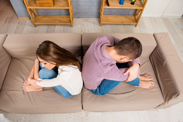 Vista dall'alto di depresed uomo e donna seduti schiena contro schiena sul divano