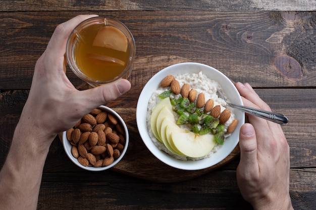 Vista dall&#39;alto di farina d&#39;avena colazione per uomo con mela, mandorle e kiwi.