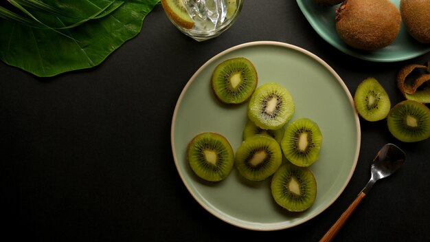 Vista dall'alto di fette di kiwi verde sul piatto in ceramica sulla tavola nera con copia spazio