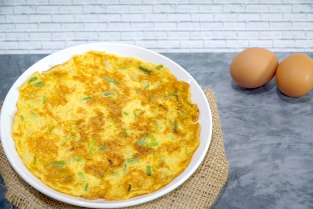 Vista dall&#39;alto di frittata (frittata, uova strapazzate) con cipolla verde sul tavolo. Stile asiatico