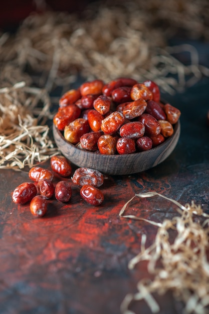 Vista dall'alto di frutti freschi di silverberry crudi all'interno e all'esterno di una ciotola di legno su uno sfondo di colori misti con spazio libero