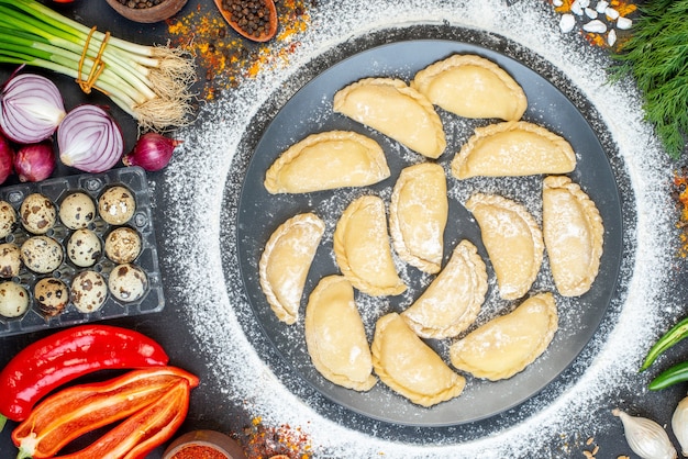 Vista dall'alto di gnocchi crudi su lastra grigia con farina intorno e set di alimenti