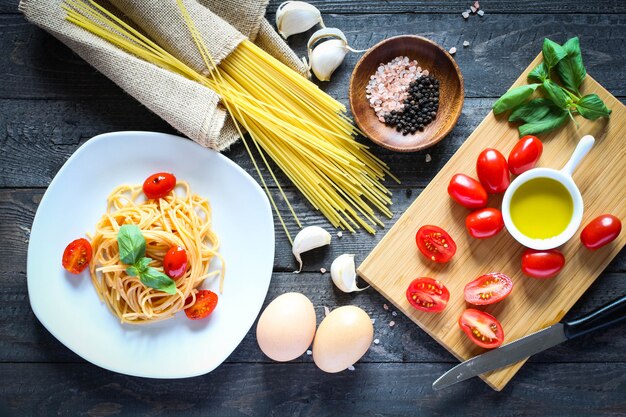 Vista dall'alto di ingredienti italiani per pomodoro e spaghetti basilici.