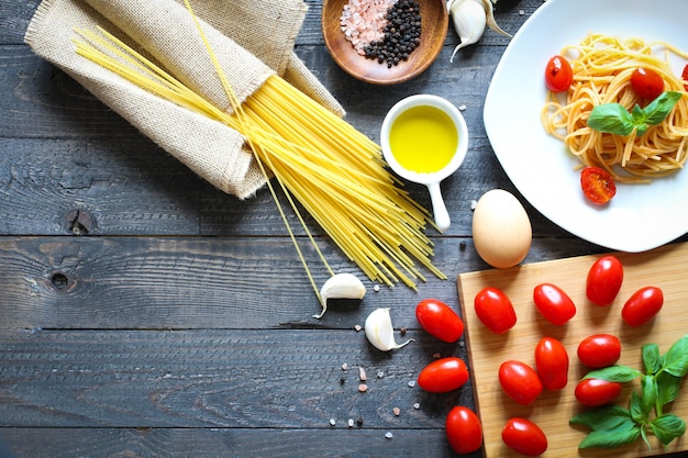 Vista dall'alto di ingredienti italiani per pomodoro e spaghetti basilici.