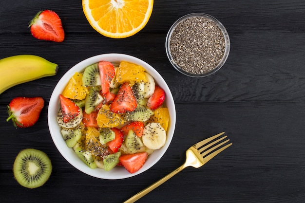 Vista dall'alto di insalata di frutta con semi di chia e ingredienti