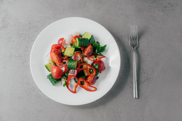 Vista dall'alto di insalata di verdure fresche preparata con peperone, ravanello, pomodori, cetrioli e prezzemolo