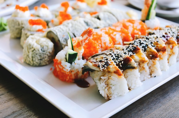 Vista dall'alto di involtini di sushi con salmone, anguilla, cetriolo, formaggio e wasabi sul piatto del ristorante