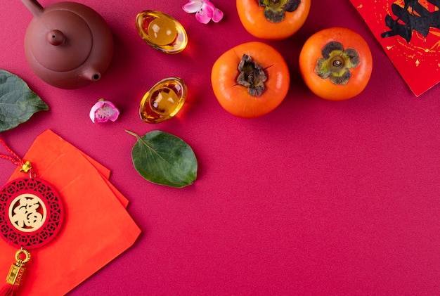 Vista dall'alto di kaki di cachi dolci freschi con foglie su sfondo rosso da tavola per il concetto di design di frutta del capodanno lunare cinese, la parola significa che la primavera sta arrivando.