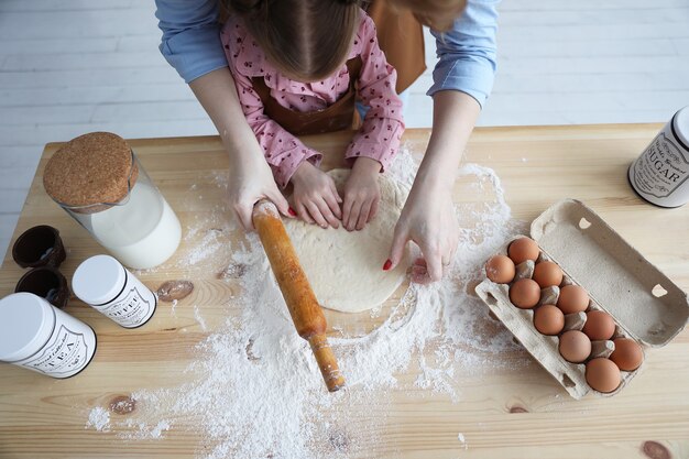 Vista dall'alto di madre e figlia in cucina che cucinano con farina e uova