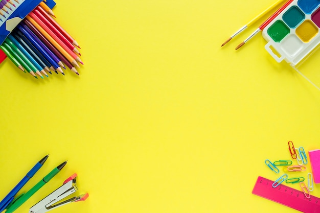 Vista dall'alto di materiale scolastico su sfondo giallo. Di nuovo a scuola