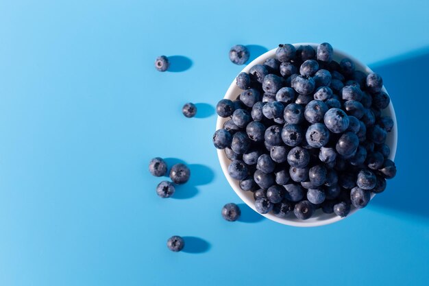 Vista dall'alto di mirtilli freschi maturi in una ciotola isolata blu Frutta naturale sana Vegana e vegetariana