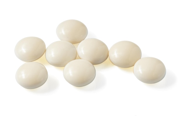 Vista dall'alto di molte pillole bianche a forma di cerchio isolate su uno sfondo bianco