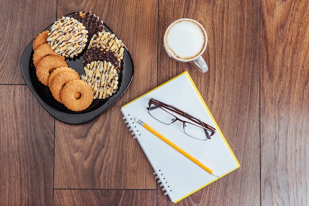 Vista dall'alto di notebook, articoli di cancelleria, strumenti di disegno e alcune tazze di caffè.