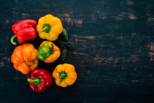 Vista dall'alto di paprika colorata fresca su sfondo di legno nero Spazio libero per il testo