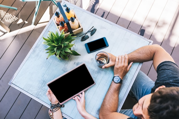 Vista dall'alto di persone con gadget su un tavolo esterno