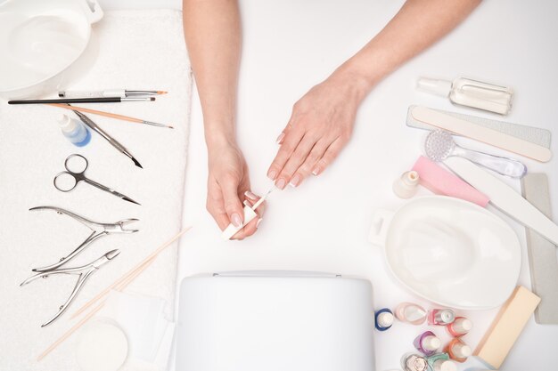 vista dall'alto di strumenti per manicure e donna che prepara le sue mani per ottenere la procedura di manicure