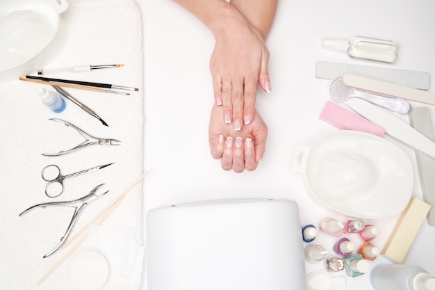 vista dall'alto di strumenti per manicure e donna che prepara le sue mani per ottenere la procedura di manicure