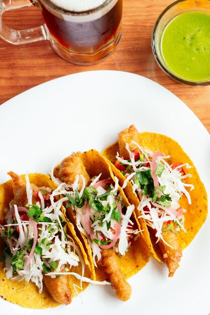 Vista dall'alto di tacos di gamberetti con salsa e barattolo di birra.