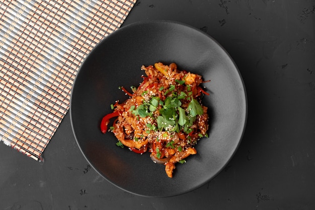 Vista dall'alto di tagliatelle wok con verdure e carne in una ciotola sul tavolo grigio
