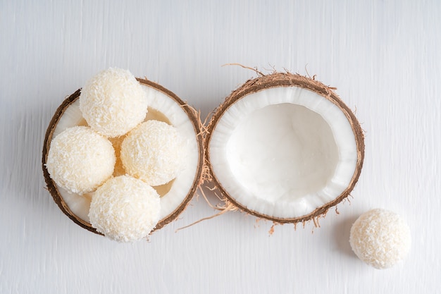 Vista dall'alto di tartufi vegani al cocco con ripieno di ricotta in metà cocco fresco su un tavolo